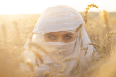 Blue-eyed woman with her face covered in a wheat field