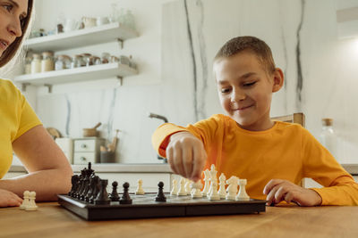 Boy playing chess with mother at home