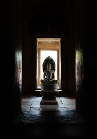 Buddha statue by window in historic building