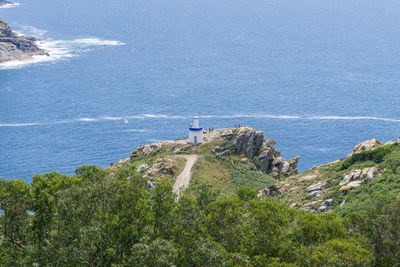 Lighthouse amidst sea and buildings against mountain