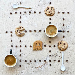 Directly above shot of coffee cups with beans and cookies arranged on table