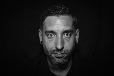 Close-up portrait of man against black background