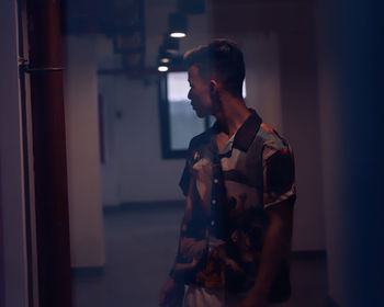 Young man looking away while standing indoors