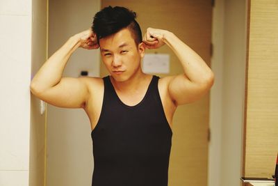Portrait of man flexing muscles against wall