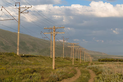 Electricity pylon on field against sky