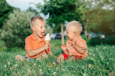 Toddler crying while brother eating ice cream on grass