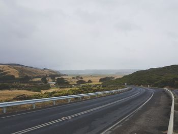 Empty road by mountains against sky