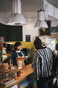 Entrepreneur talking with customer at checkout counter in food store