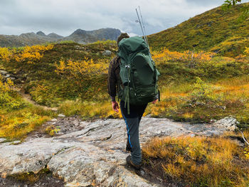 Rear view of man standing on mountain against sky