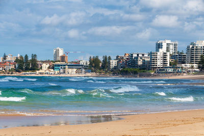 Buildings by sea against sky in city