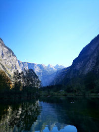 Scenic view of lake and mountains against clear blue sky