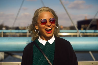 Portrait of smiling young woman standing against lake