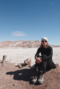 Full length of woman sitting on land against sky