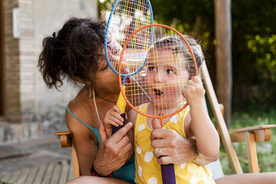 Grandmother playing with little girl and badminton rackets outdoors