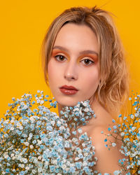 Portrait of beautiful woman against yellow background