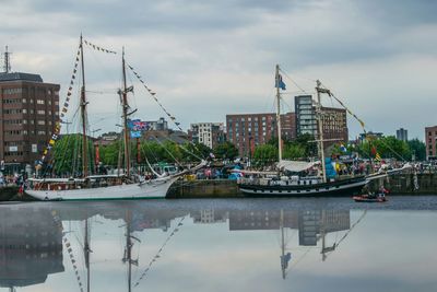 Sailboats in harbor against sky in city