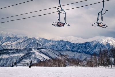 Ski lift over snowcapped mountains against sky