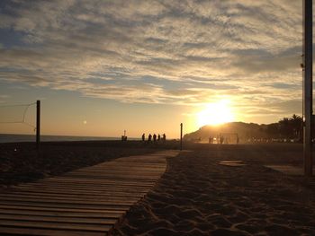 People on beach against sky during sunset