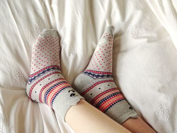 Low section of woman wearing socks relaxing on bed at home