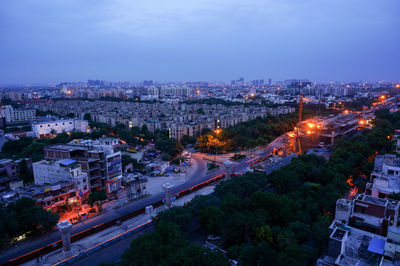 High angle view of illuminated city against blue sky