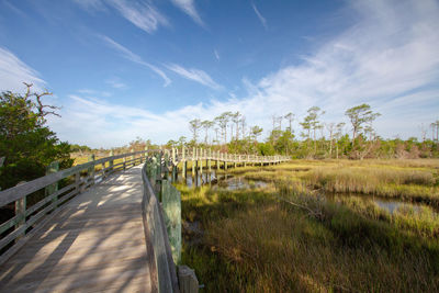 Scenic view of coastal marsh against sky with boardwalk pathway 