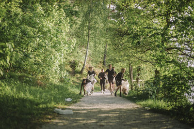 Boys and coach plogging on footpath amidst green plants