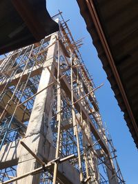 Low angle view of crane and building against blue sky