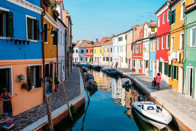 Boats moored in canal amidst buildings in city