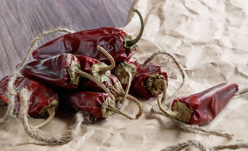 Close-up of dry red chili peppers with rope on paper bag at table