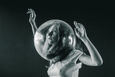 Low angle view of young woman wearing glass helmet in head against black background