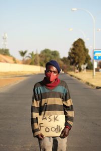 Portrait of homeless man standing on the road asking for food wearing a covid-19 nask