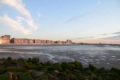 Buildings by sea against sky during sunset