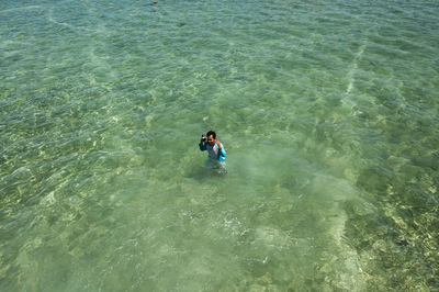 High angle view of man with camera standing in sea