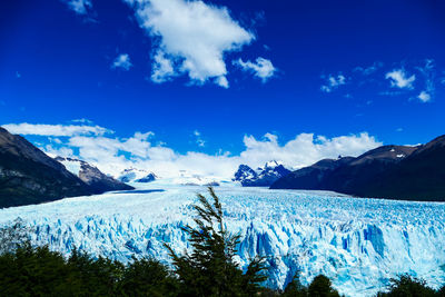 Scenic view of snowcapped mountains against blue sky