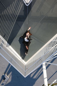 High angle view of young woman lying down on elevated walkway