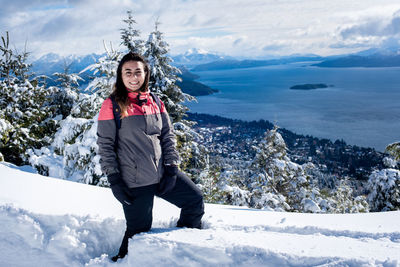 Full length of smiling woman on snow covered mountains