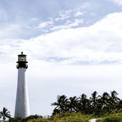 Low angle view of lighthouse by building against sky