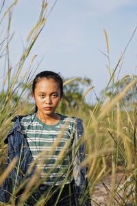 Portrait of girl standing on field against sky