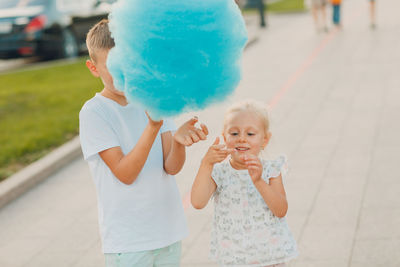 Brother and sister holding cotton candy in park