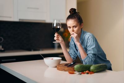 Portrait of young man holding wineglass while sitting at home