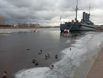 Boats moored on sea against sky in city