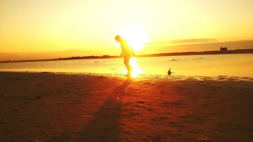 Silhouette people standing on beach against sky during sunset