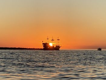 Ship sailing on sea against sky during sunset