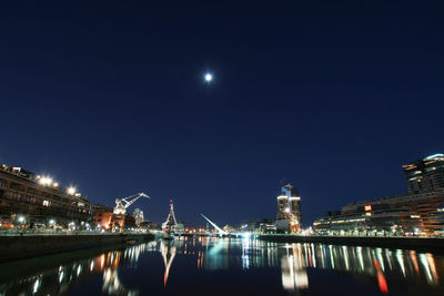 Illuminated bridge over river against sky at night