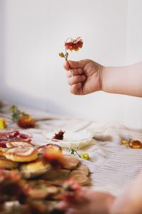 Cropped hand of child holding wilted flower at table