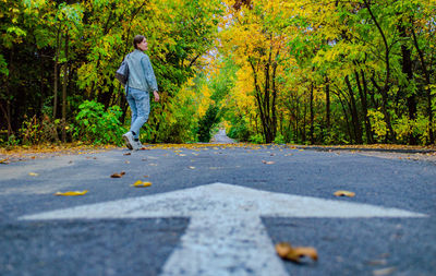 Rear view of woman walking on road