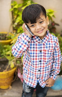 Cute boy holding mobile phone standing outdoors
