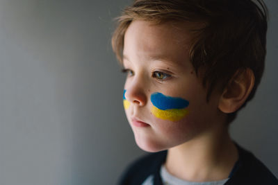 Portrait of a ukrainian boy with a face painted with the colors of the ukrainian flag.