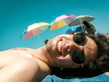 Portrait of man wearing sunglasses against blue sky