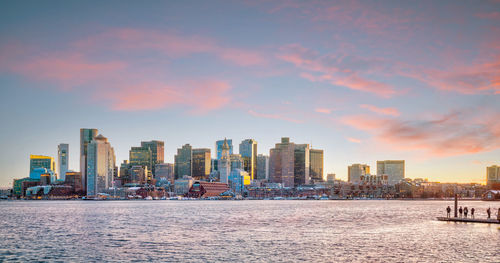 Modern buildings in city against sky during sunset